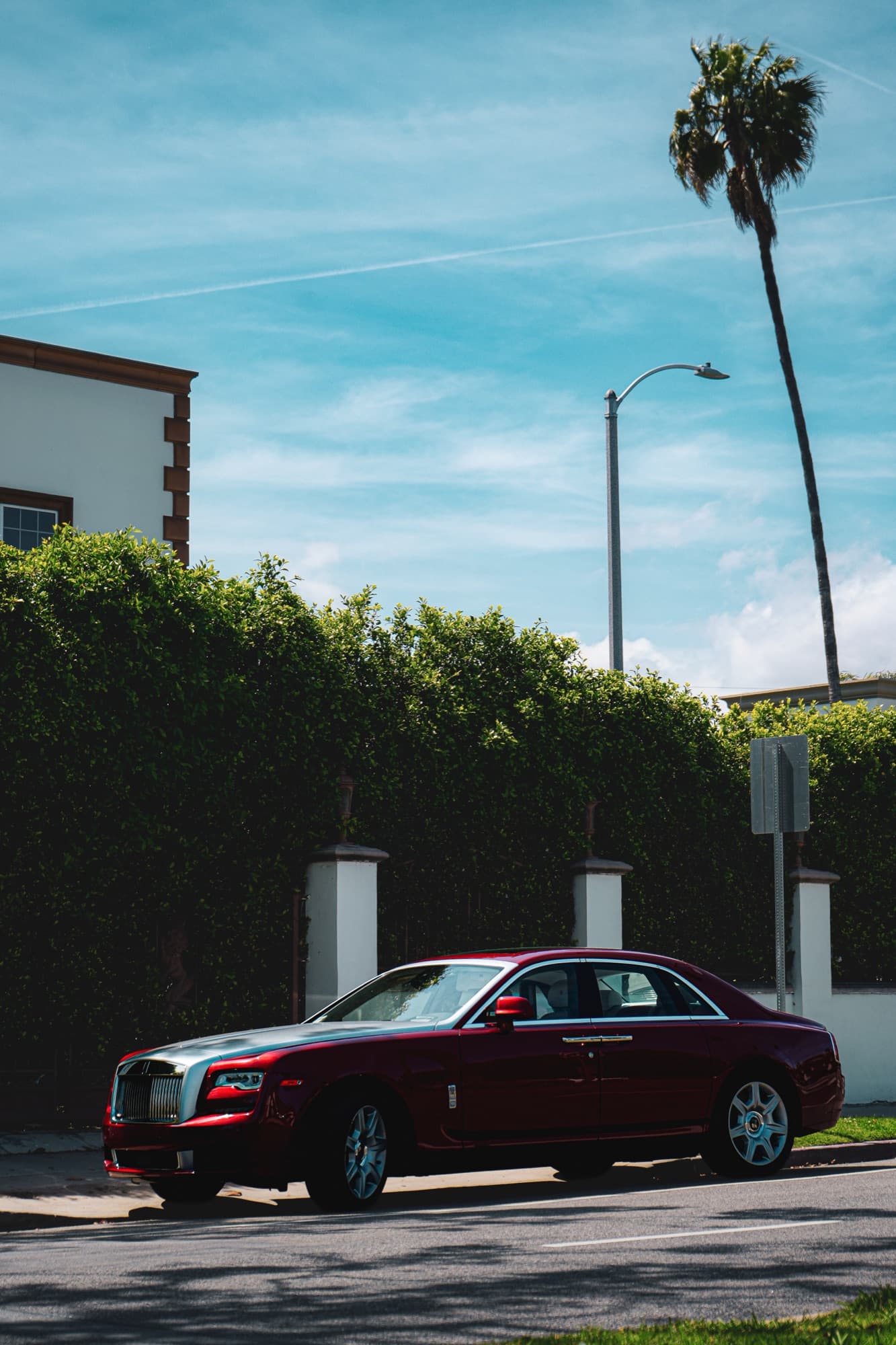 Car parked outside a gated, hedge-screened residence on a quiet street